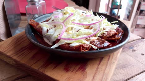 delicious enchiladas enmoladas with lettuce, onions, and sour cream in a close-up shot