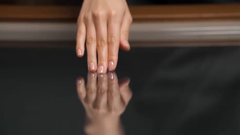 close-up of a hand with a clear reflection on a dark, glossy surface