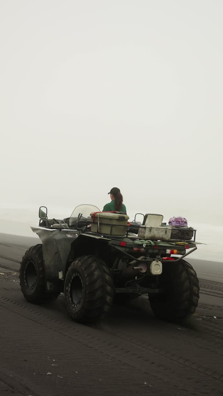 Donna alla guida di un quad su una spiaggia nebbiosa