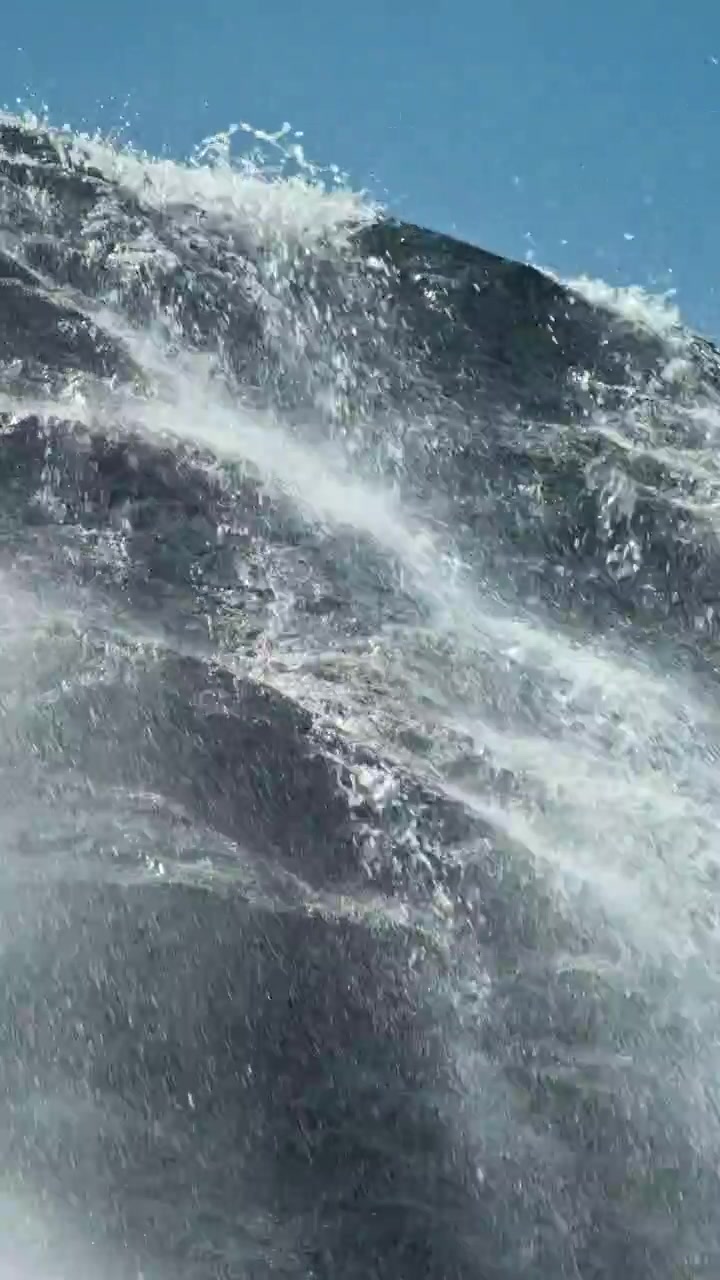 Powerful Waterfall with Water Splashing Over Dark Rocks