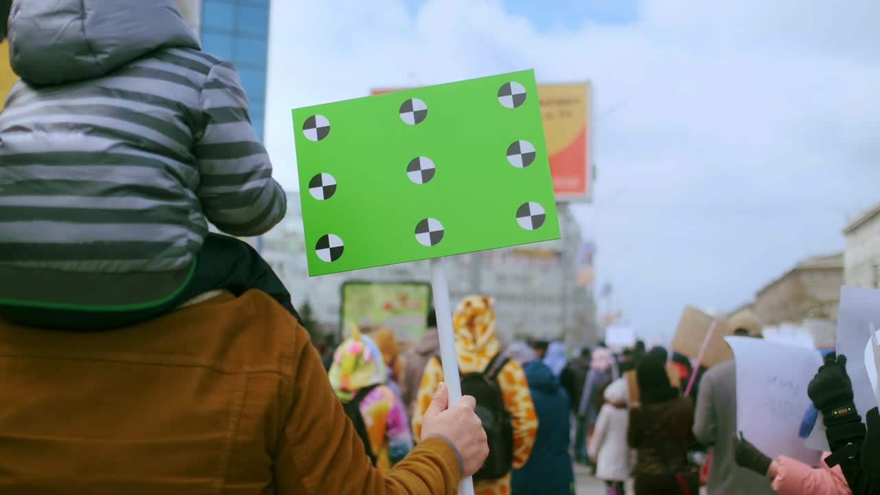 아버지와 아들의 가족은 빈 크로마키 우주 모형 배너를 들고 집회에 참석했습니다.