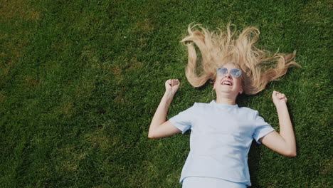 happy child with long hair lies on the lawn