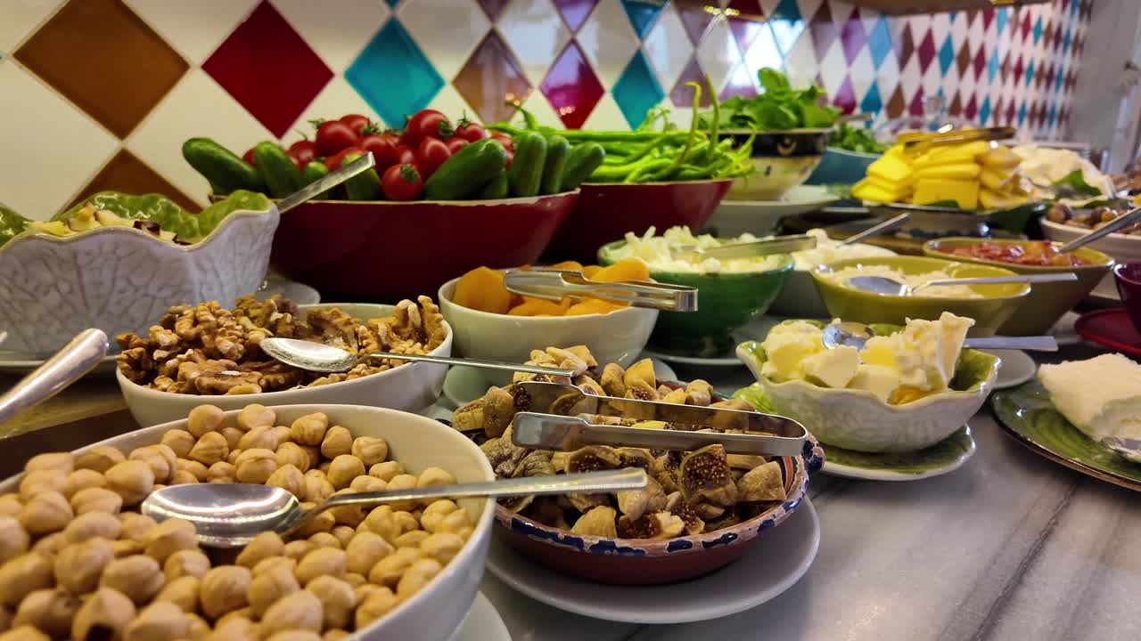 A vibrant and diverse buffet spread featuring a variety of fresh vegetables, nuts, dried fruits, and cheese
