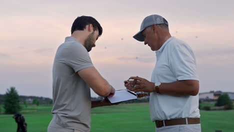 Golfmänner-Unterzeichnen-Dokumentvertrag-Auf-Golfplatz.-Zwei-Geschäftsleute-Machen-Einen-Deal.