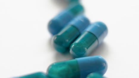 very bright vertical close-up from top to bottom of dark blue and green capsules on a white surface