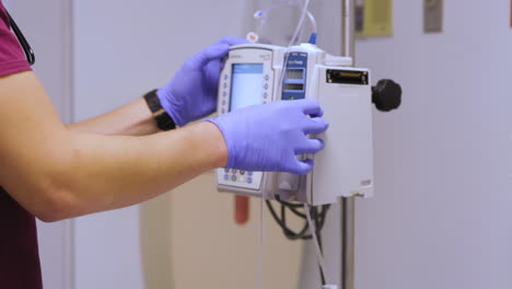 hospital ward: professional male nurse does checkup of patient's vitals, checking heart rate computer, intravenous or iv fluids drip bag