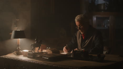 old passionate man writes down a note in his office at night