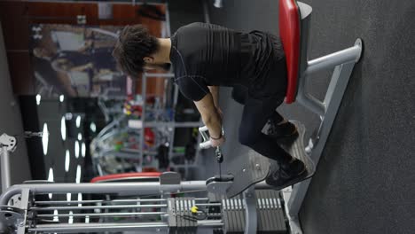 determined man doing cable row exercise at gym