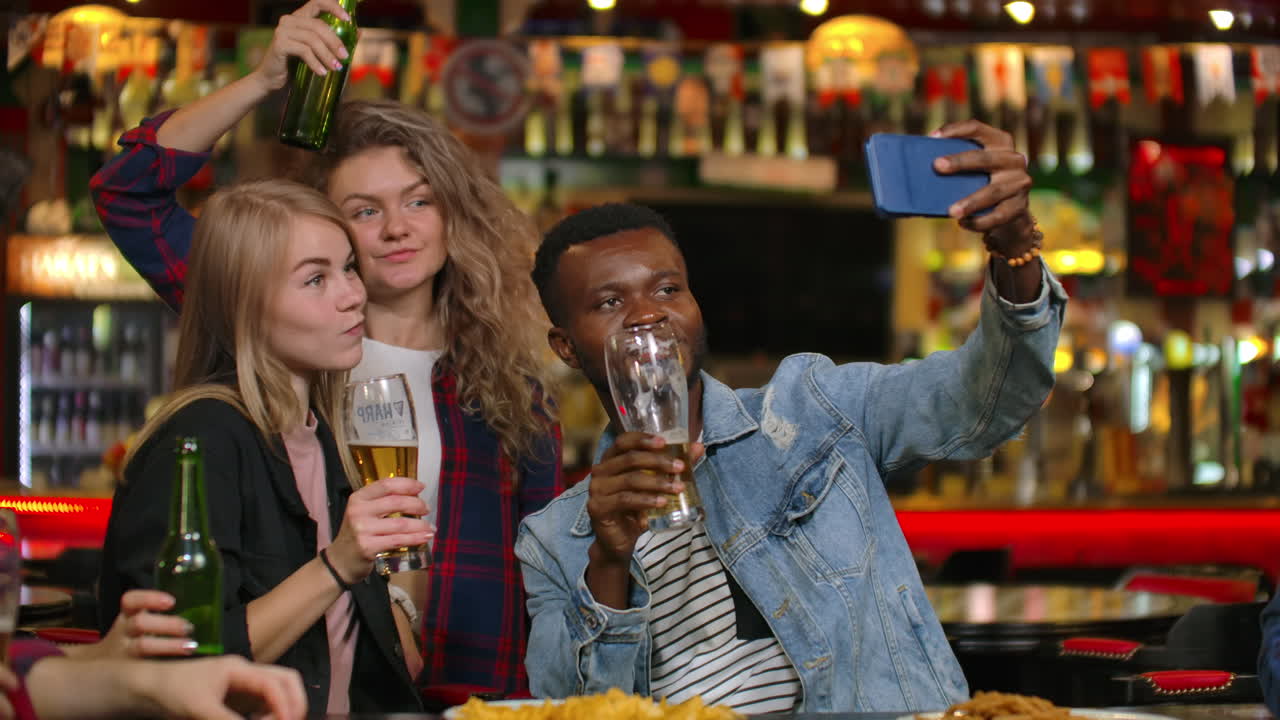 Amici che scattano foto con il telefono al bar, creano una foto condivisa sul telefono. Festa con amici al bar con birra.