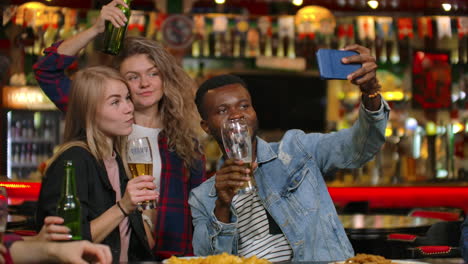 Los-Amigos-Toman-Fotografías-Por-Teléfono-En-El-Bar-Y-Hacen-Una-Foto-Compartida-Por-Teléfono.-Fiesta-Con-Amigos-En-El-Bar-Con-Cerveza.