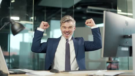 happy mature bearded business man employee working on pc computer celebrates successful yes gesture. working in moderm office stroke of luck, wins big.