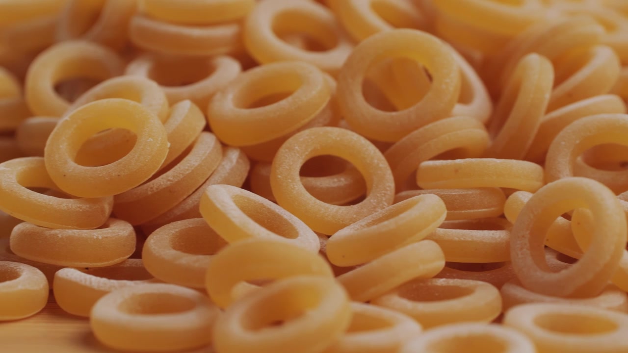 Pasta integrale biologica, maccheroni di semola di grano duro, penne rigate crude in una ciotola di legno. Filmato 4k di alta qualità