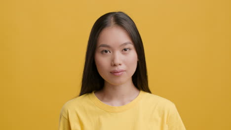 happy asian woman showing ok gesture on yellow background