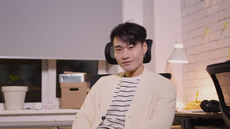 사무실 의자에 앉아서 카메라를 보고 웃는 젊은 남자의 초상화
