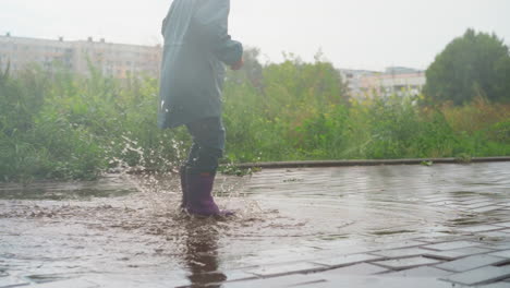 una niña salpicando en un charco en un día de lluvia