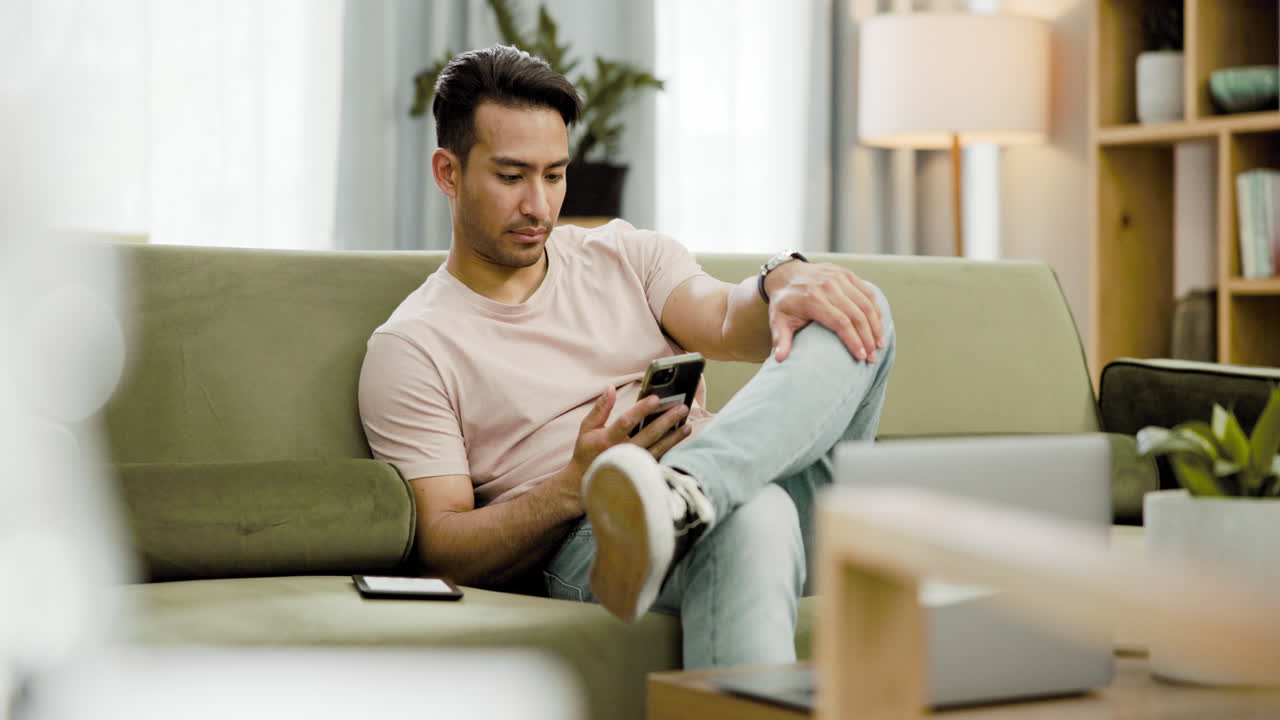 집에서 소파에서 전화를 사용하는 남자