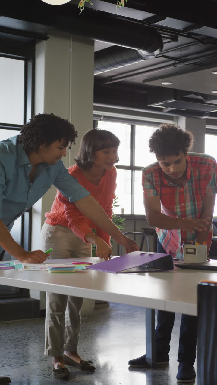 video vertical de personas de negocios felices y diversas discutiendo el trabajo durante una reunión en la oficina