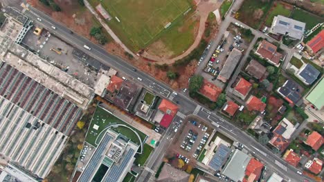 una fotografía aérea en ángulo hacia abajo por encima de una carretera, que muestra el tráfico, los edificios industriales y los campos de fútbol a continuación