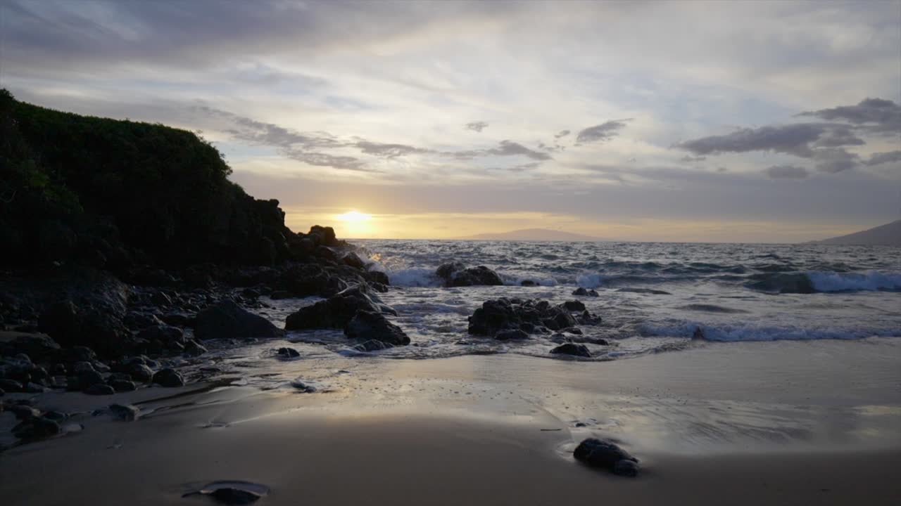 bajando la escena en cámara lenta de una playa rocosa al atardecer en maui hawaii
