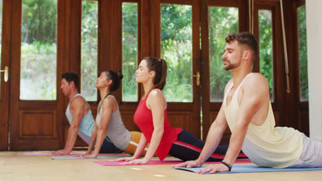 diverse group in yoga position stretching on mats during yoga class at health studio