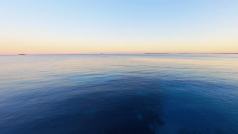 fpv aerial drone flying fast across the blue water of the mediterranean at sunset