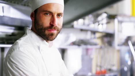 chef masculino de pie con los brazos cruzados en la cocina comercial