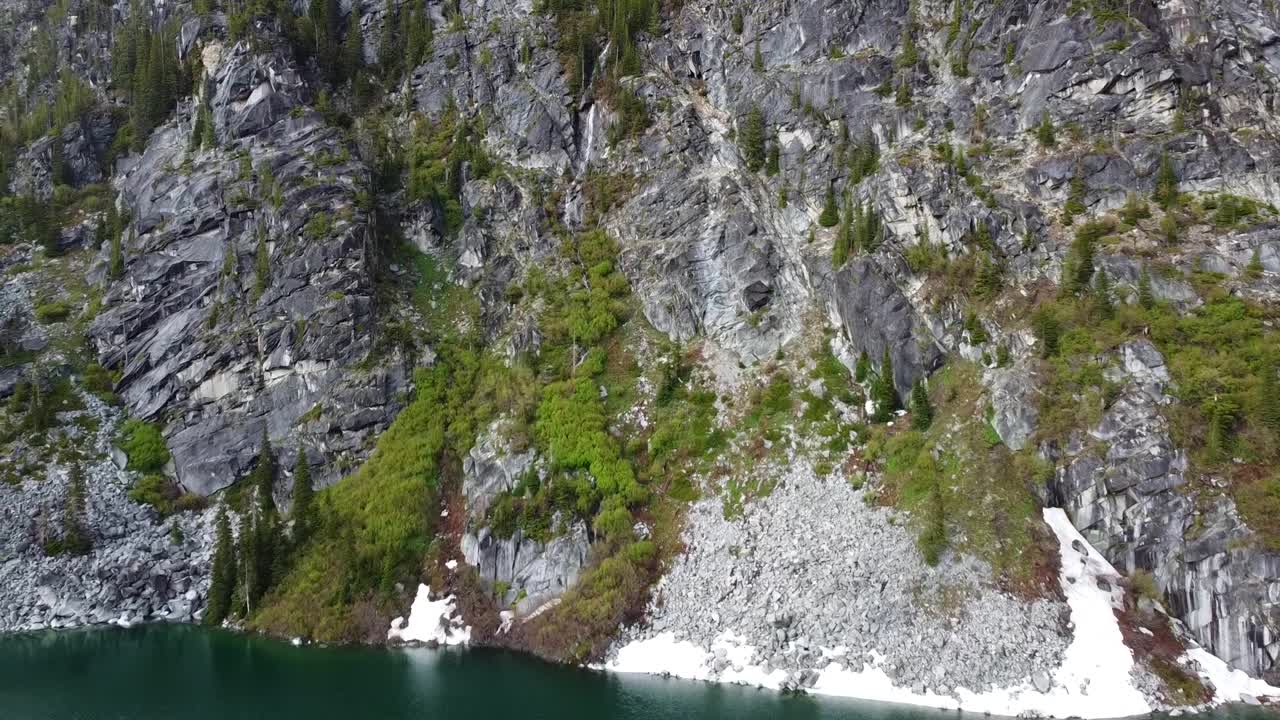 Záběry z dronu horského vodopádu a jezera Colchuck poblíž The Enchantments v Kaskádovém pohoří ve Washingtonu – mech a stromy rostou na útesu