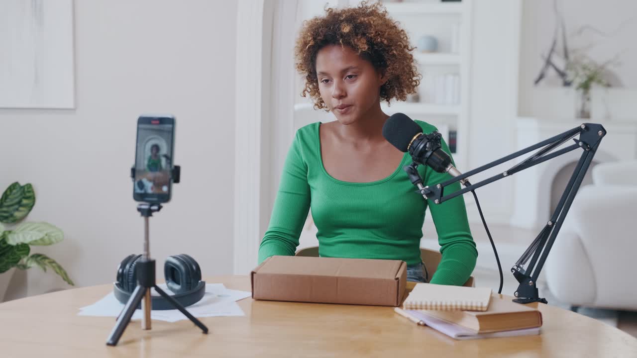 Young african american woman blogger starting filming video unpacking at phone
