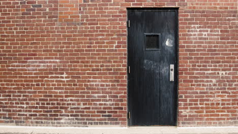 Puerta-De-Madera-Negra-En-Callejón-De-Ladrillo