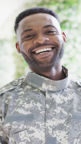vertical video portrait of happy african american male soldier smiling outdoors, slow motion