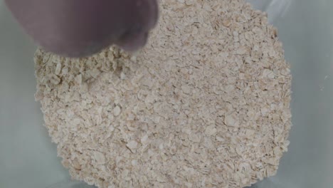 pouring half cup of quick oats into bowl, overhead closeup