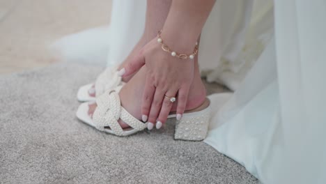 close-up of a bride's foot wearing a delicate white wedding heel with pearl details, ready for the ceremony