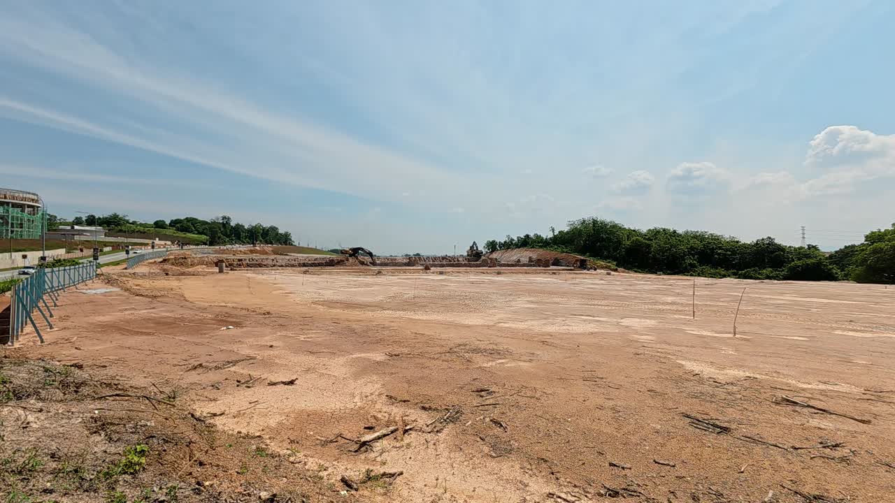 Extensive earthworks at a large construction site. Heavy machinery is used to level the ground, cutting into hills and filling in ravines to prepare the land for building new homes