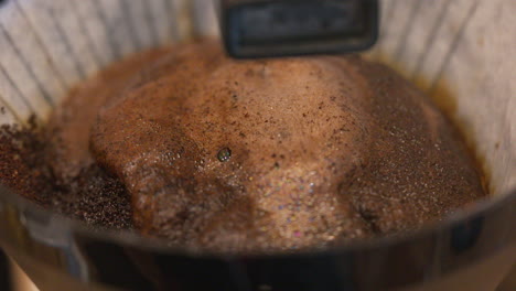 Hot-water-dripping-and-percolating-ground-coffee-beans-in-a-filter-over-a-pot