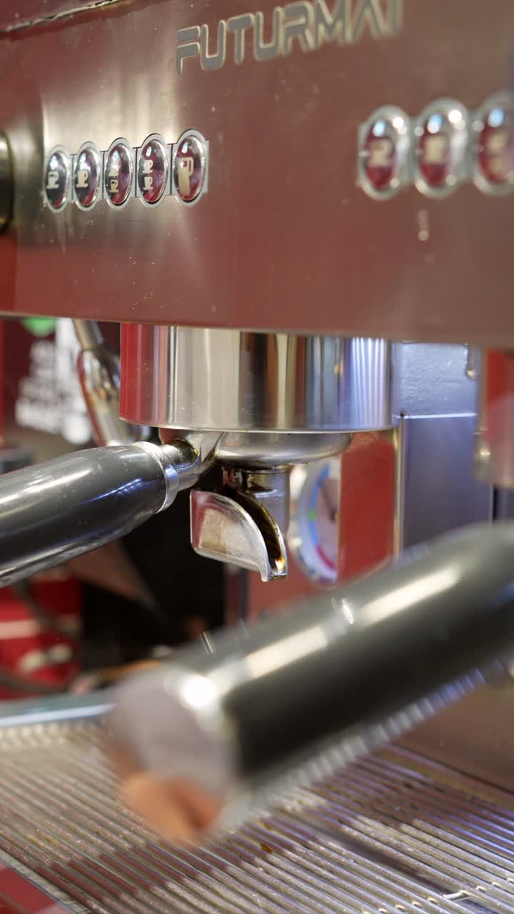 Primo piano di un barista che blocca il portafiltro nella macchina da caffè espresso.