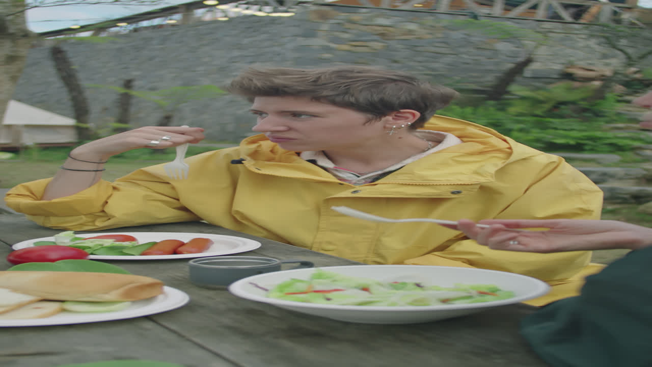 Young Woman Eating Meal and Chatting with Friends at Glamp