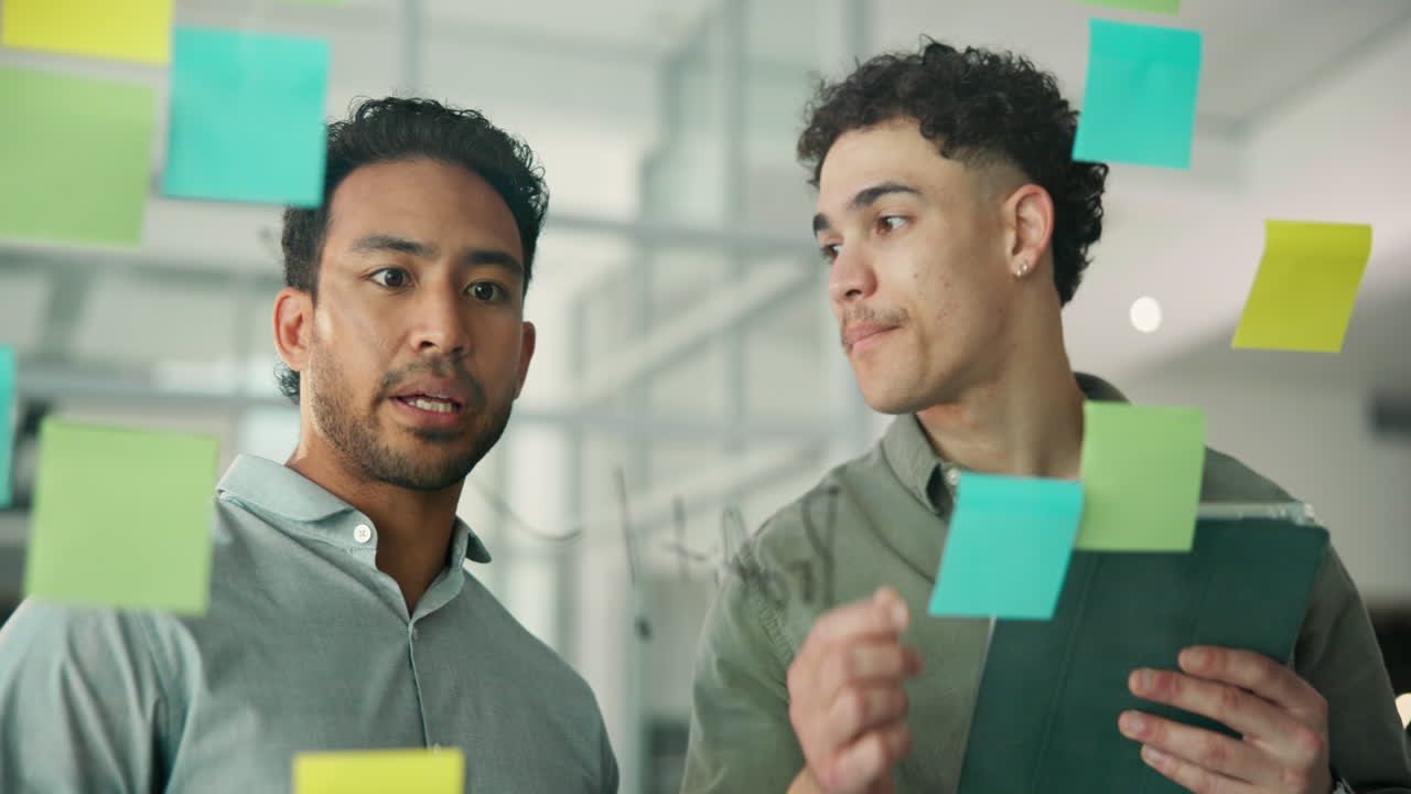 Two Businessmen Brainstorming Ideas on a Glass Board with Sticky Notes