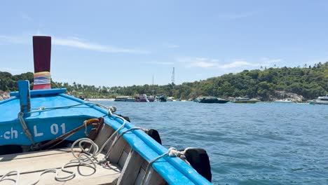 a boat glides through chalong bay, phuket, under clear skies, capturing serene ocean views and lush landscapes