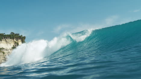Turquoise wave crashes and sprays in slow motion with foamy white crest