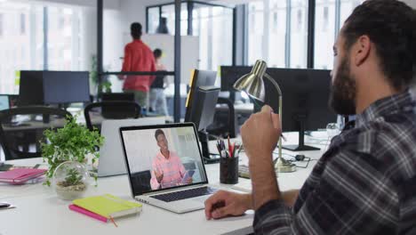 hombre de oriente medio teniendo una videollamada con un colega masculino en una computadora portátil en la oficina