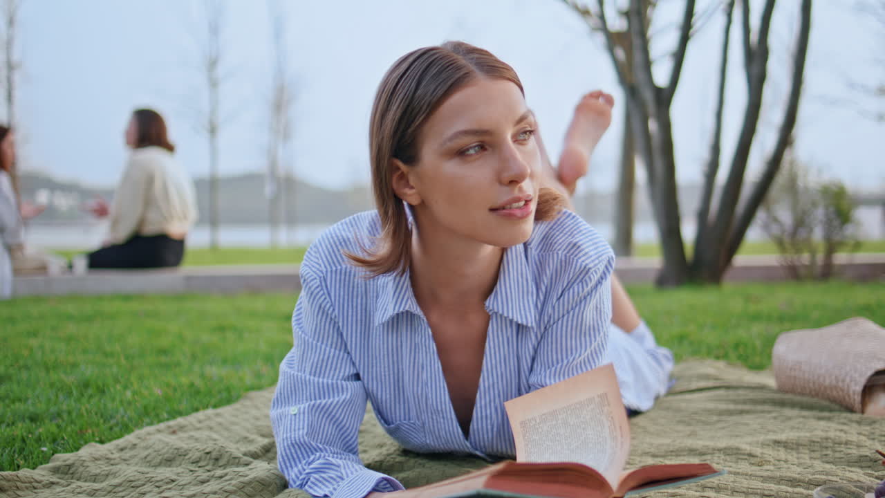 Reading woman lying grass in peaceful park setting closeup. Romantic lady picnic