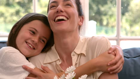 happy mother and daughter sitting on the couch with flowers