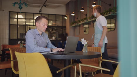 Young freelancer man working on computer at home. Casual concentrated entrepreneur developing new project while working on laptop at home. Male professional typing laptop keyboard at office workplace
