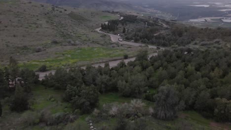 Aerial-tilt-up-following-Car-on-Countryside-Road-surrounded-grass,-Foggy---Golan-Heights