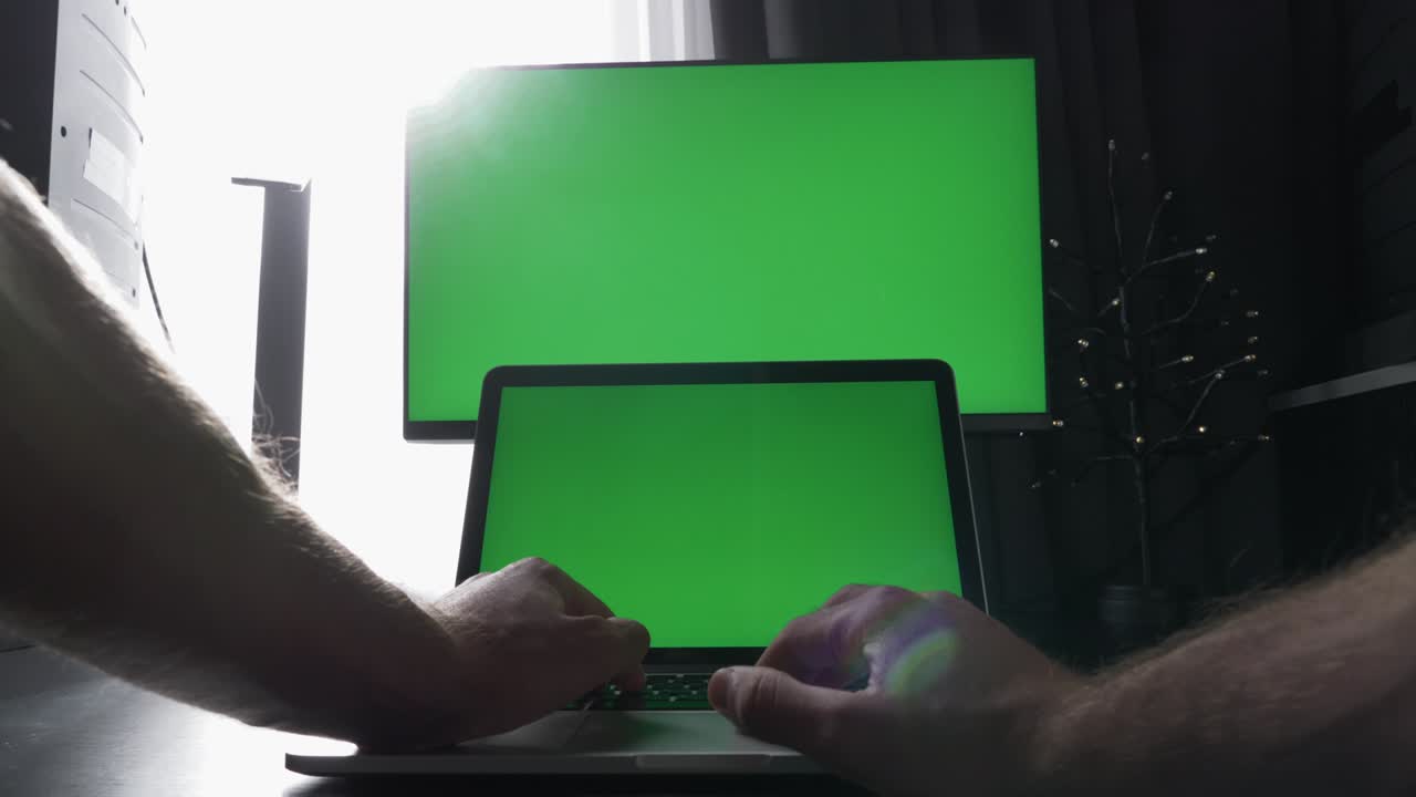 freelance it hombre está trabajando en línea en portátil con pantallas verdes. programador masculino está usando computadora con pantalla verde clave de croma, escribiendo algoritmo en el teclado. concepto de tecnología