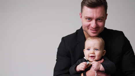 smiling caucasian male embracing a cute baby. happy daddy kissing his lovely child on the head and holding him tight. white backdrop.