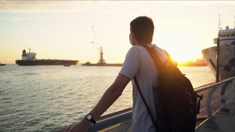 rear view of a guy looking at peaceful seascape during golden hour at the port of puerto ingeniero white, buenos aires, argentina