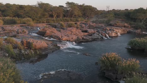 slow descending drone shot of a rocky section in the komati river with water streaming into a large pool