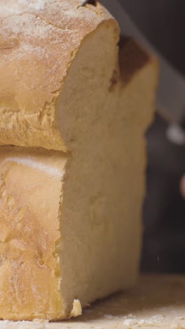 video vertical de primer plano de una persona cortando rebanadas de pan fresco de pan