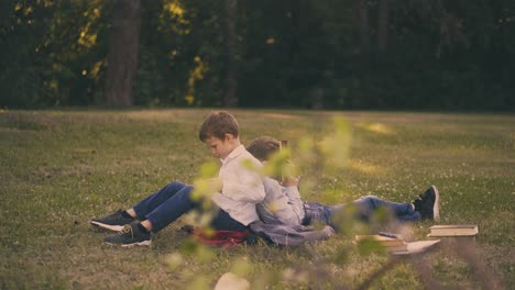 Schuljungen,-Die-Es-Satt-Haben,-Hausaufgaben-Zu-Machen,-Sitzen-Auf-Dem-Grünen-Rasen